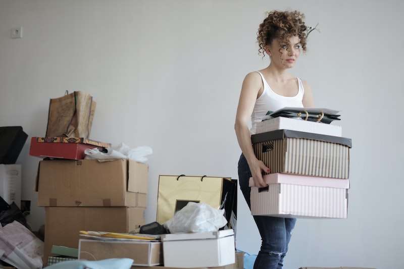Woman carrying several boxes and moving away from a pile of boxes