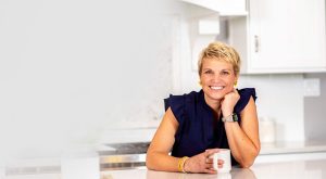 Home organizing expert Susan Stewart sitting at clean, organized kitchen counter