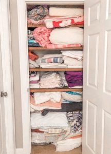 linen closet before being organized by top rated professional organizers