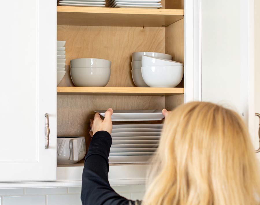 Professional Organizer St. Louis placing dishes in an organized kitchen cabinet