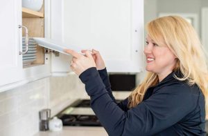 St. Louis-based professional organizer Mandy Meininger placing a plate in a kitchen cabinet